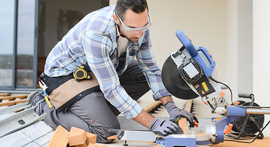 Man with safety glasses cutting wood with saw