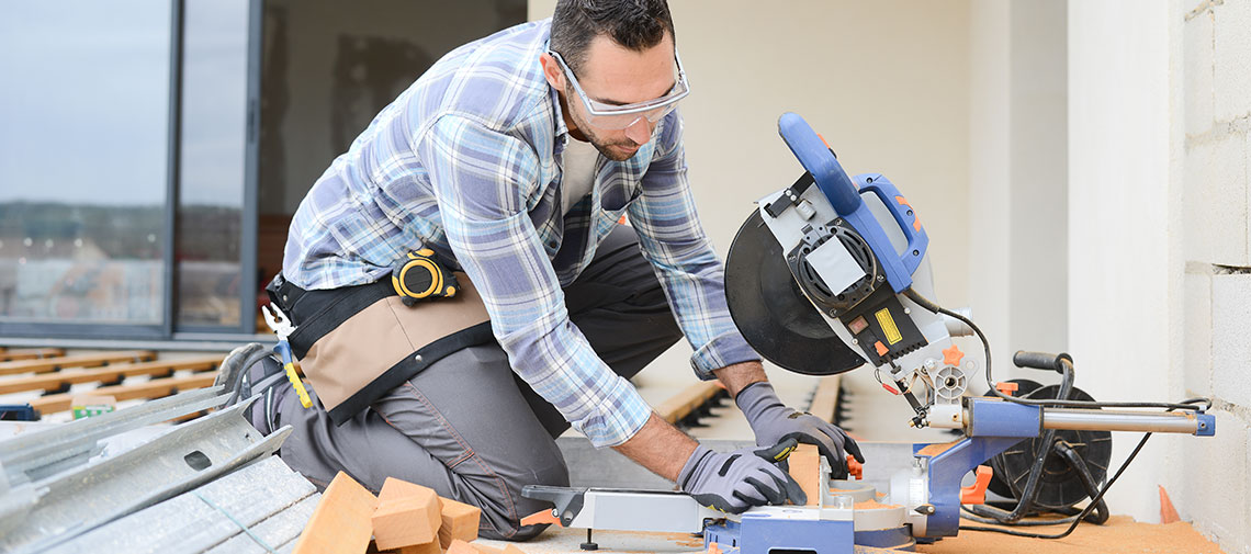 5-home-improvements-to-make-in-2022 Man with safety glasses cutting wood with saw