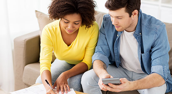 Young couple sitting on the couch looking over finances