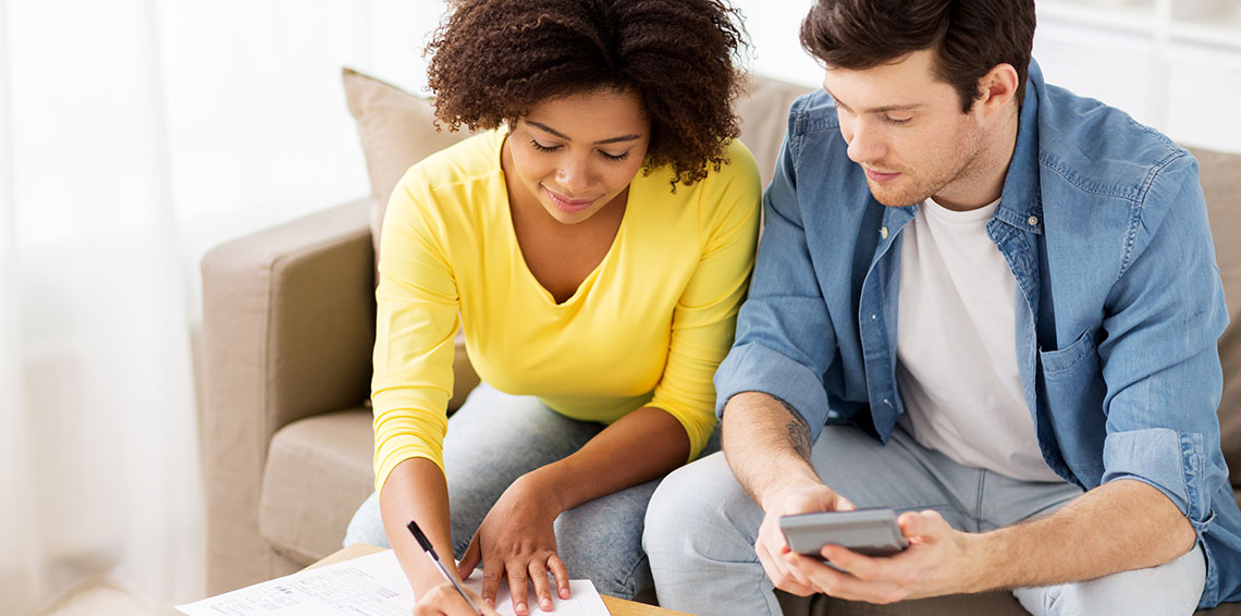 Young couple sitting on the couch looking over finances