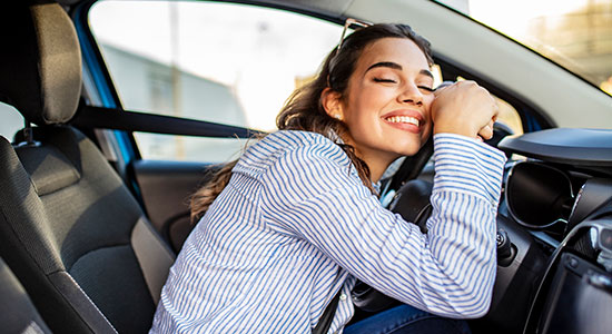 thumbnailfor A young woman hugs the steering wheel in her new car