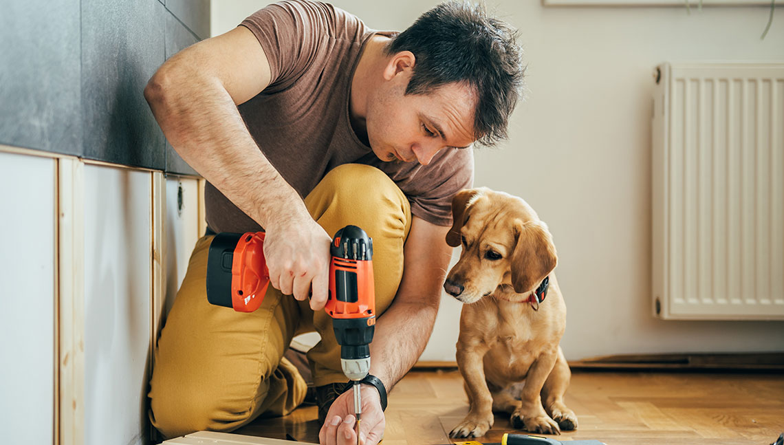Man repairing house while his dog watches
