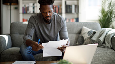 A man sits on his couch reviewing important documents