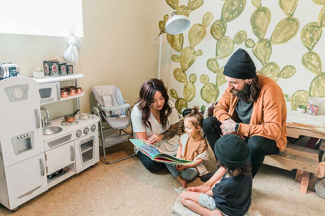 Mother and Father reading childrens book to son and daughter