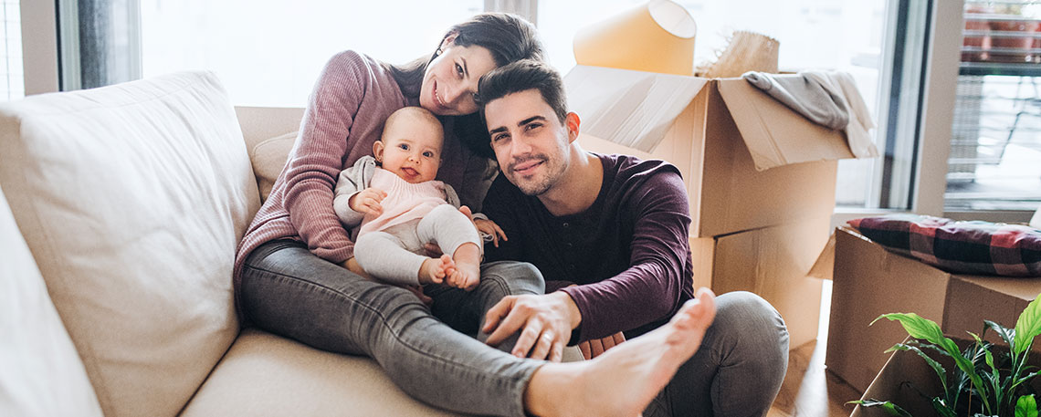 Young couple sitting on the couch with their baby