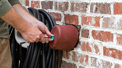 A man puts an insulated cover on an outdoor water spigot