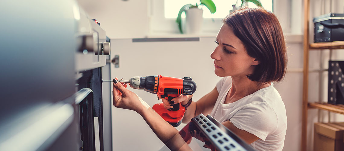 Woman using a drill to make home repairs
