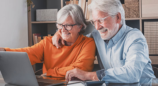 Elderly couple reviewing mortgage documents on laptop