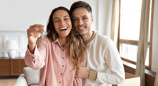 Happy young couple holding keys to first house