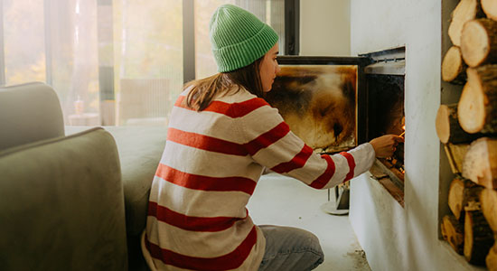 woman-adding-wood-to-fireplace-550x300