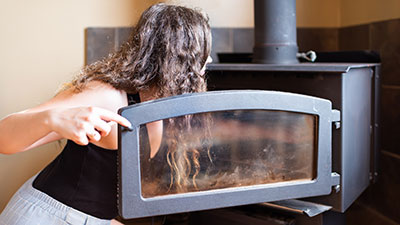 Woman inspecting a woodburning stove