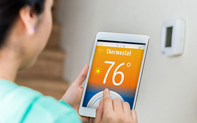 A woman controls her smart thermostat with a tablet