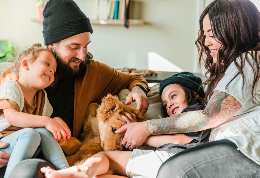 Family of four sitting on couch with dog