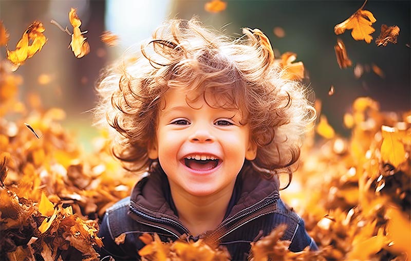 Young boy playing in a pile of leaves