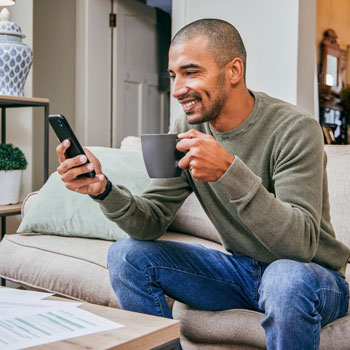 Man looking at messages on his phone from the comfort of home