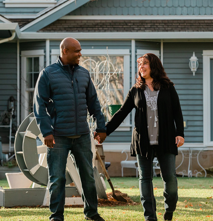stories11 Couple holding hands beside refinanced home