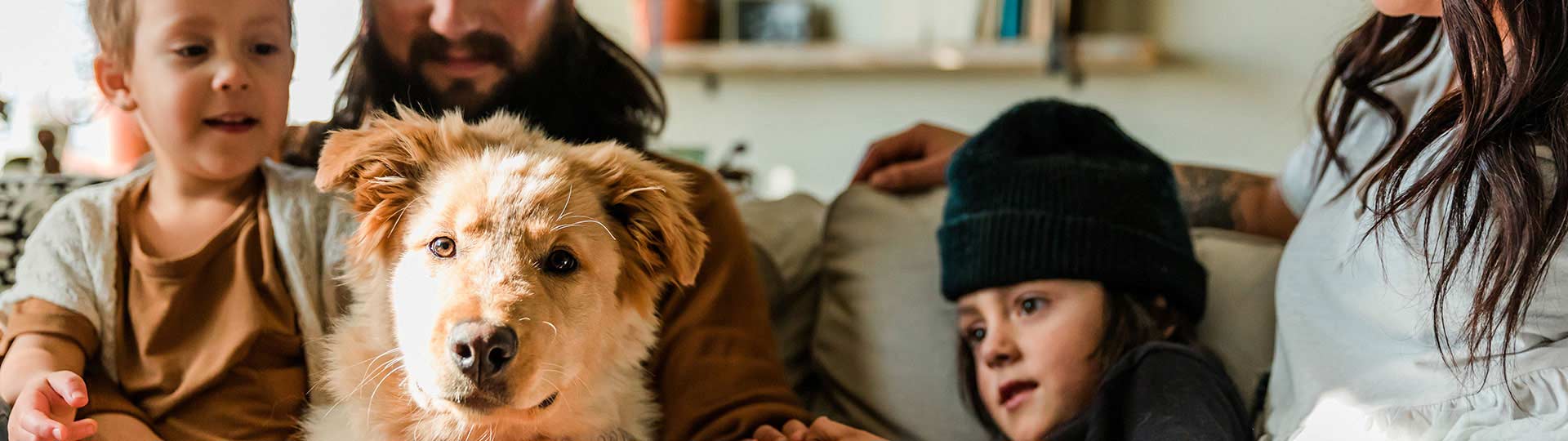 Family of four sitting on couch with dog