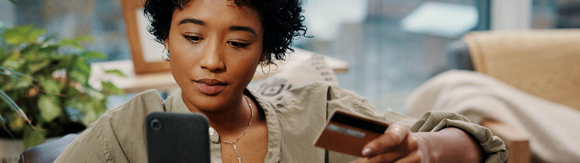 Woman looking at phone with credit card in hand