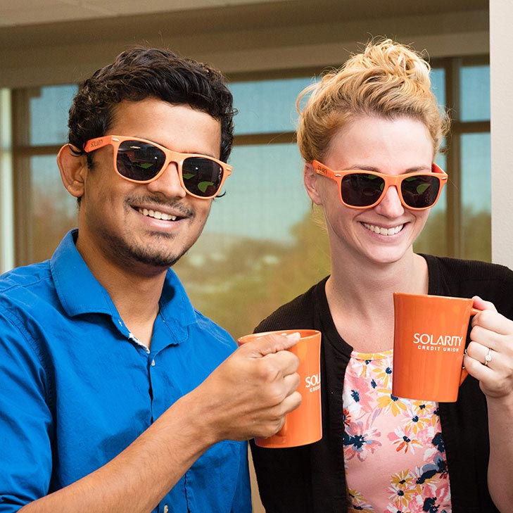 Two Solarity employees holding orange coffee mugs